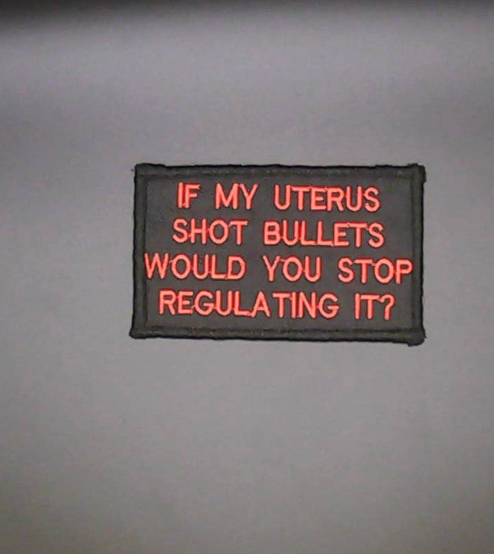 A rectangular embroidered patch with  bright red text that reads, 'IF MY UTERUS SHOT BULLETS WOULD YOU STOP REGULATING IT?' on Black background.
Sew-on Patch