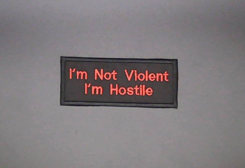A rectangular Sew-on Patch with red  text reading 'I'm Not Violent I'm Hostile' on black background.